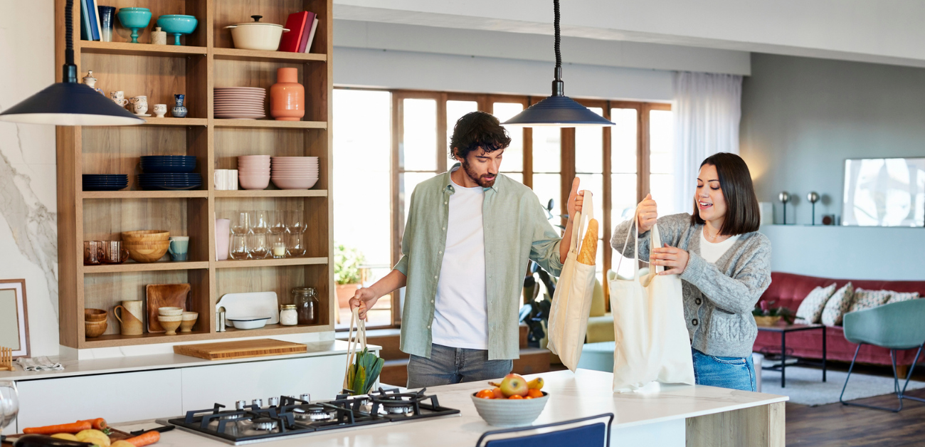 Man and woman carry cloth grocery bags into kitchen
