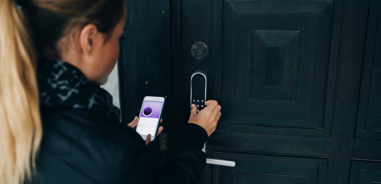 Woman opening a front door smart lock.