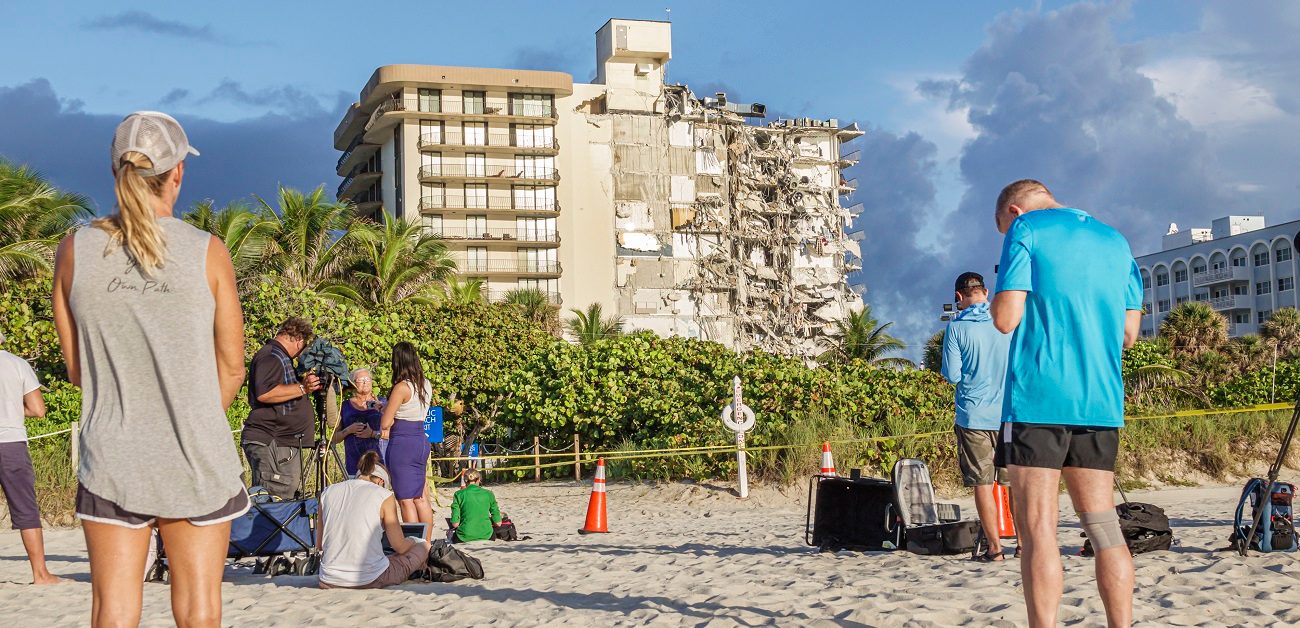 Local residents gather on the beach to look at the collapsed Champlain Towers condominium building in Surfside, Fla.