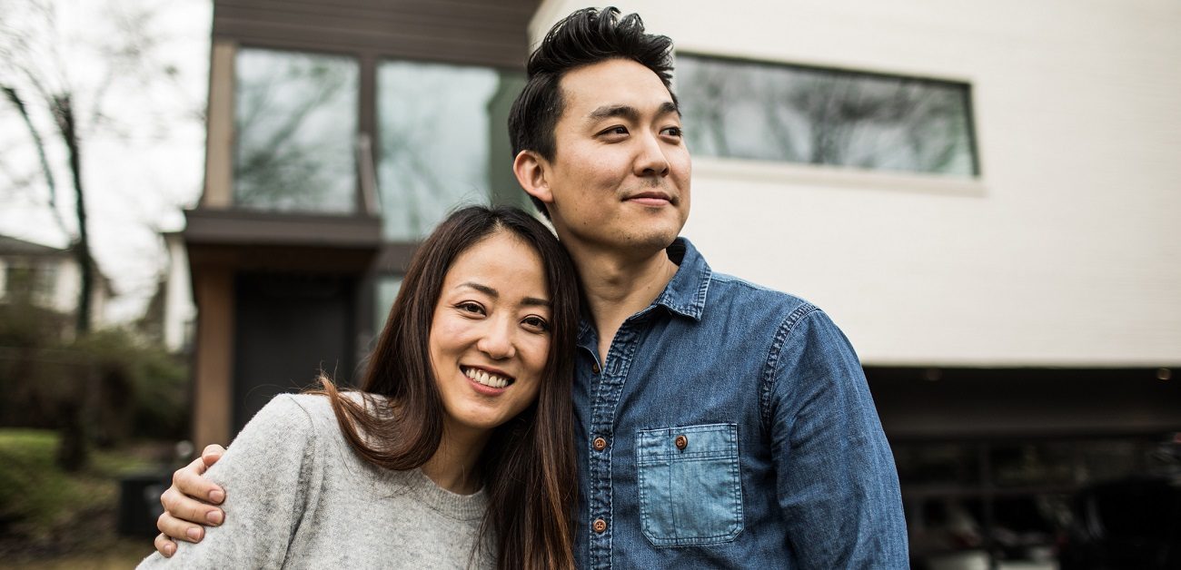 young Asian couple in front of new home