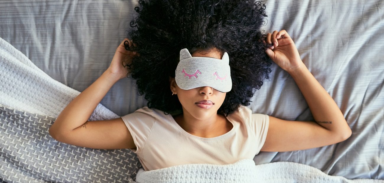 young woman sleeping with a mask on in bed