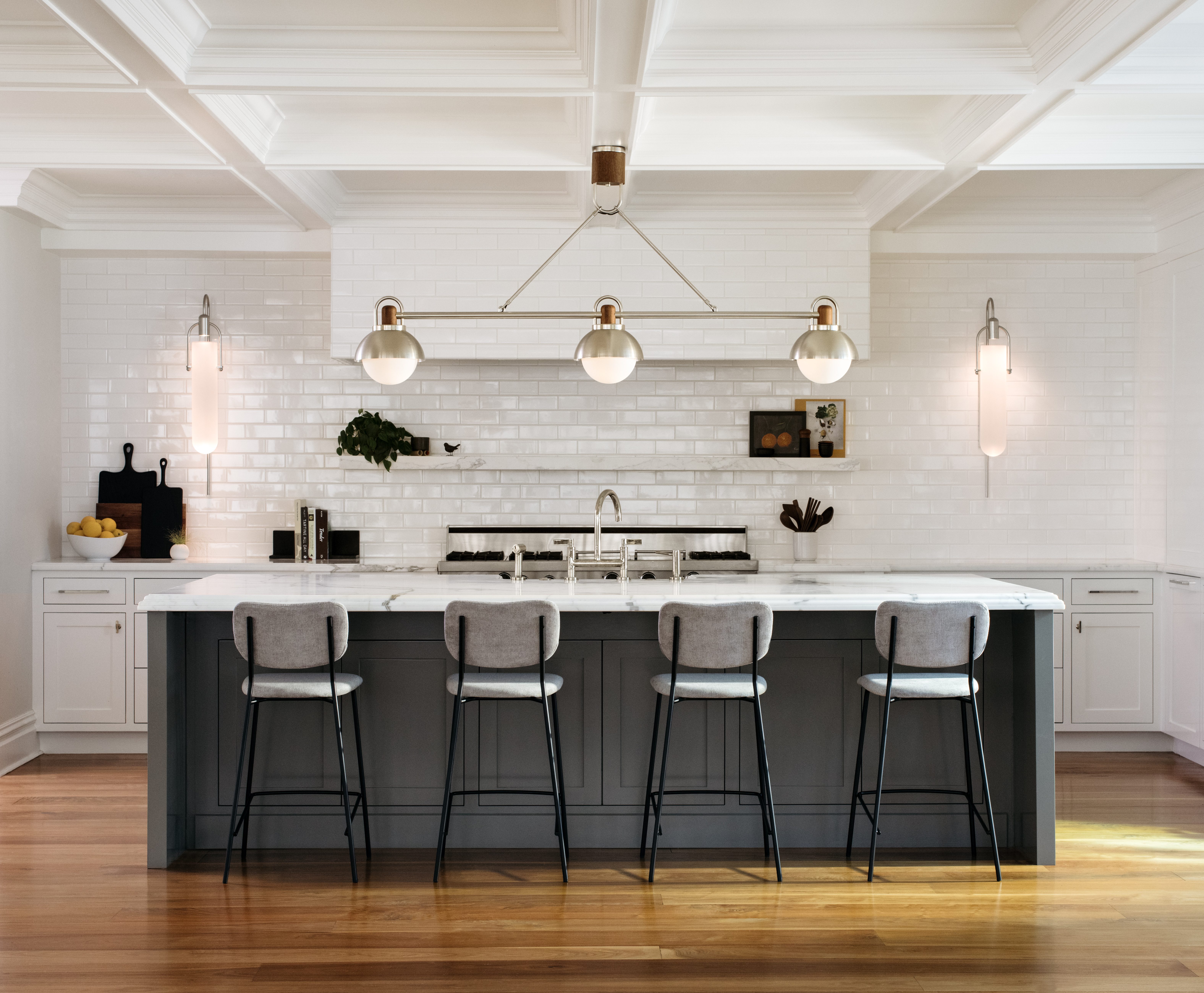 A picture of a newly renovated kitchen with modern industrial chic lighting and stools at a tall counter.