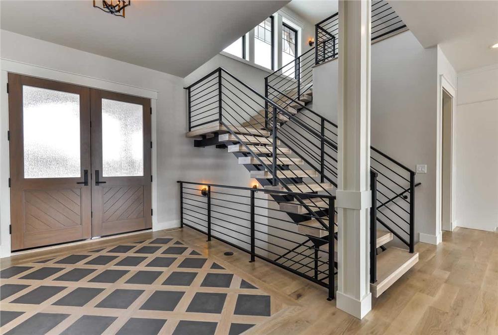 A photo of the foyer of a home facing the front door and a hardwood staircase.