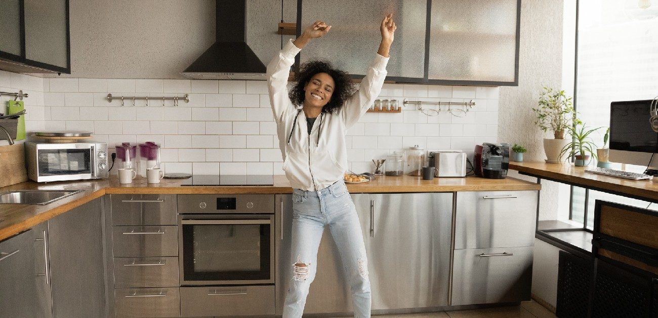 A woman in a new home dances in her kitchen.