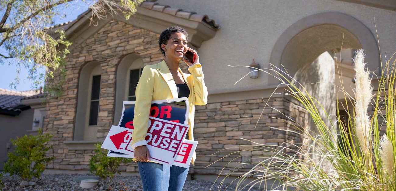 Real estate agent outside home with open house sign