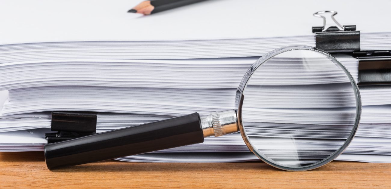 magnifying glass in front of stack of papers