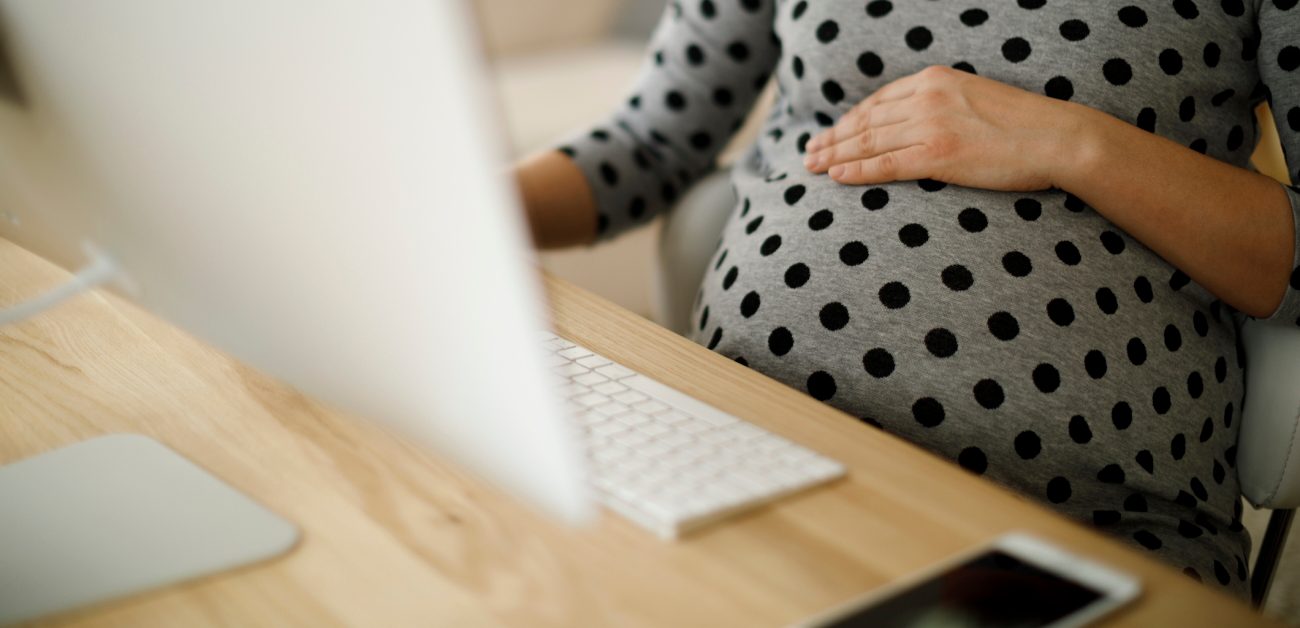 A pregnant person working at a laptop