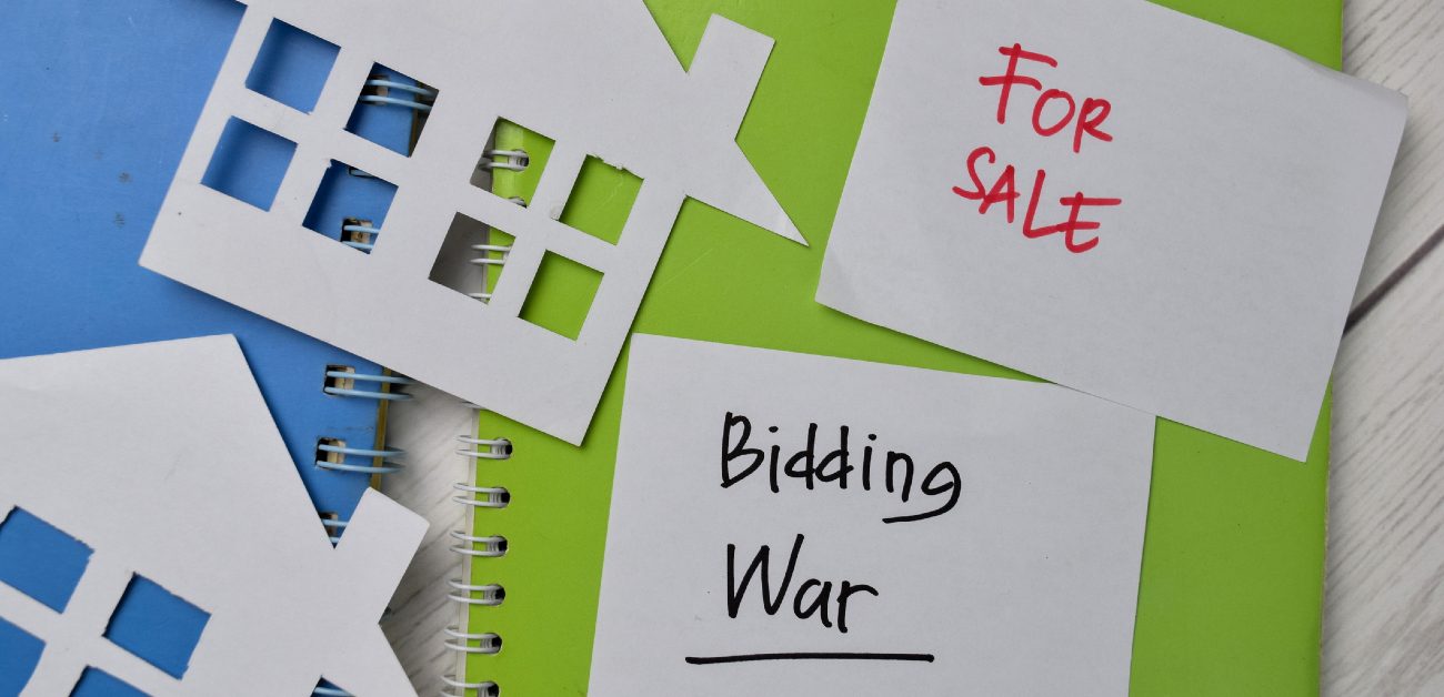 A picture of two closed notebooks with index cards on top, one saying "For Sale" and the other saying "Bidding War"