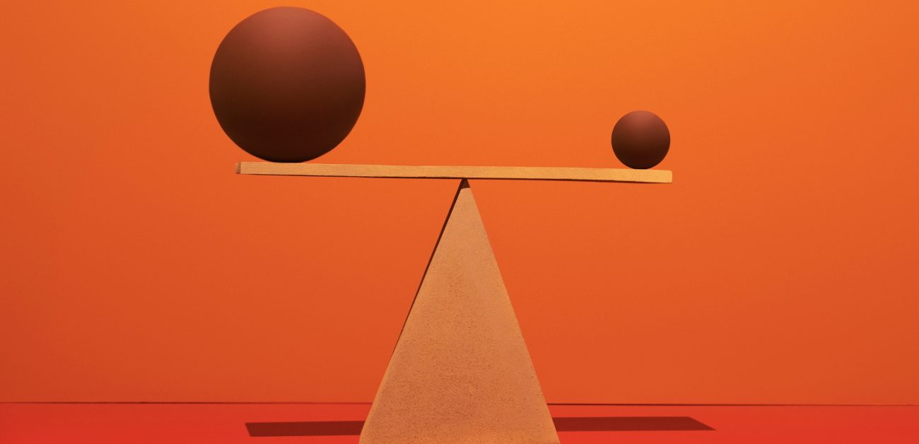 A large and a small sphere balanced on a bar on a fulcrum