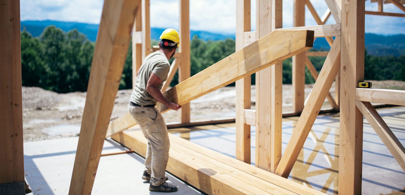 Construction worker holding wooden beam.