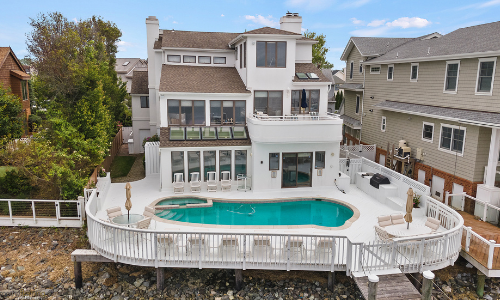 Large, white, 3-story home with pool and deck