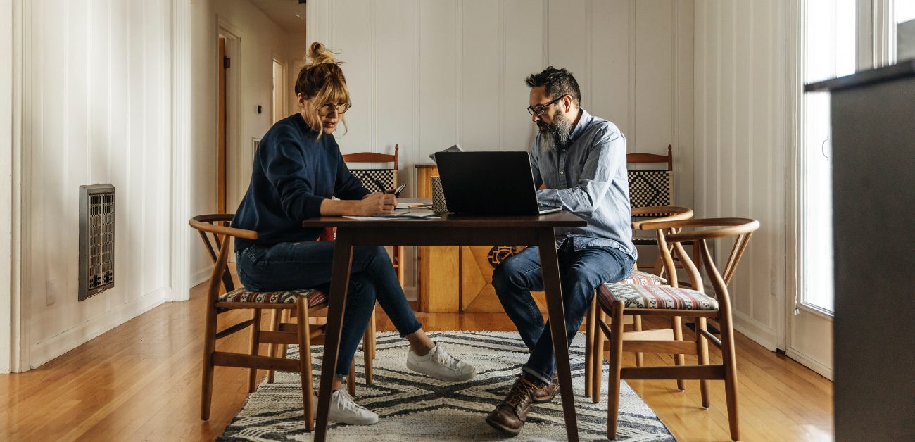 A man and a woman at a table working on laptops