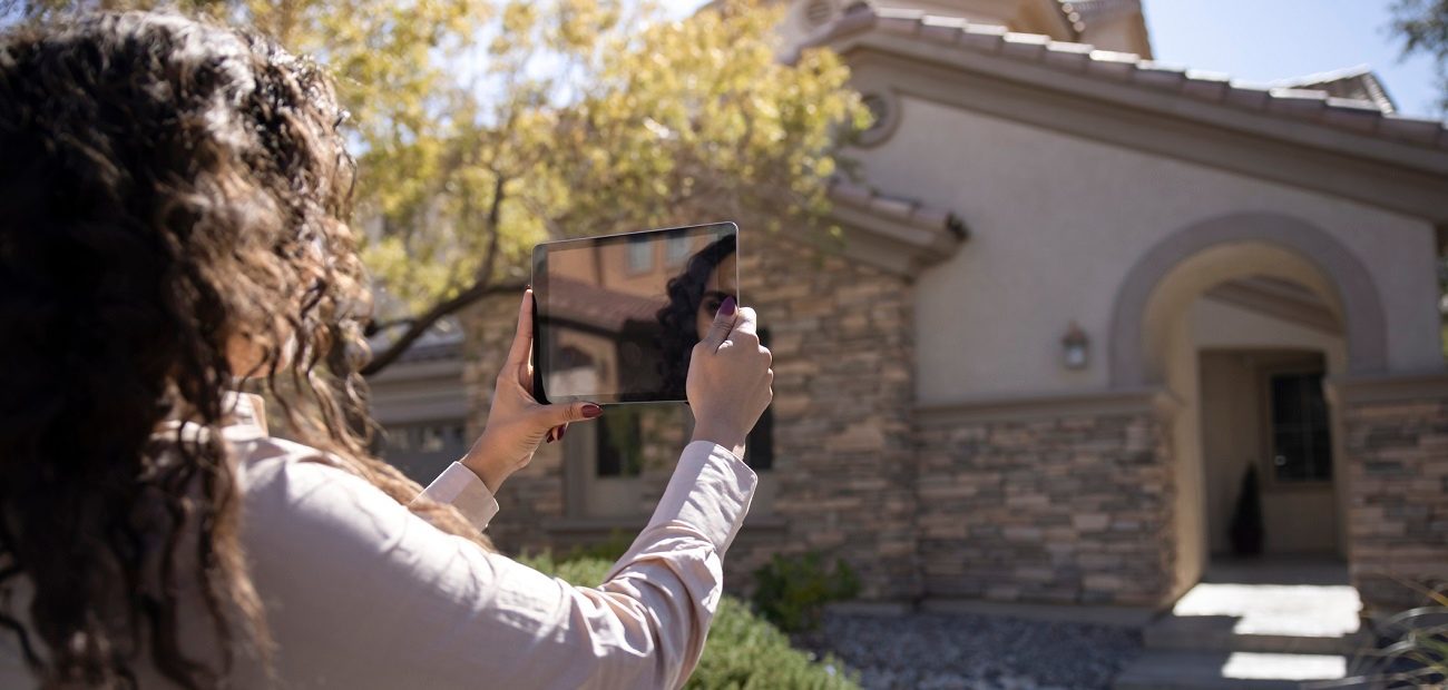 Woman Taking Photo of Home With Tablet