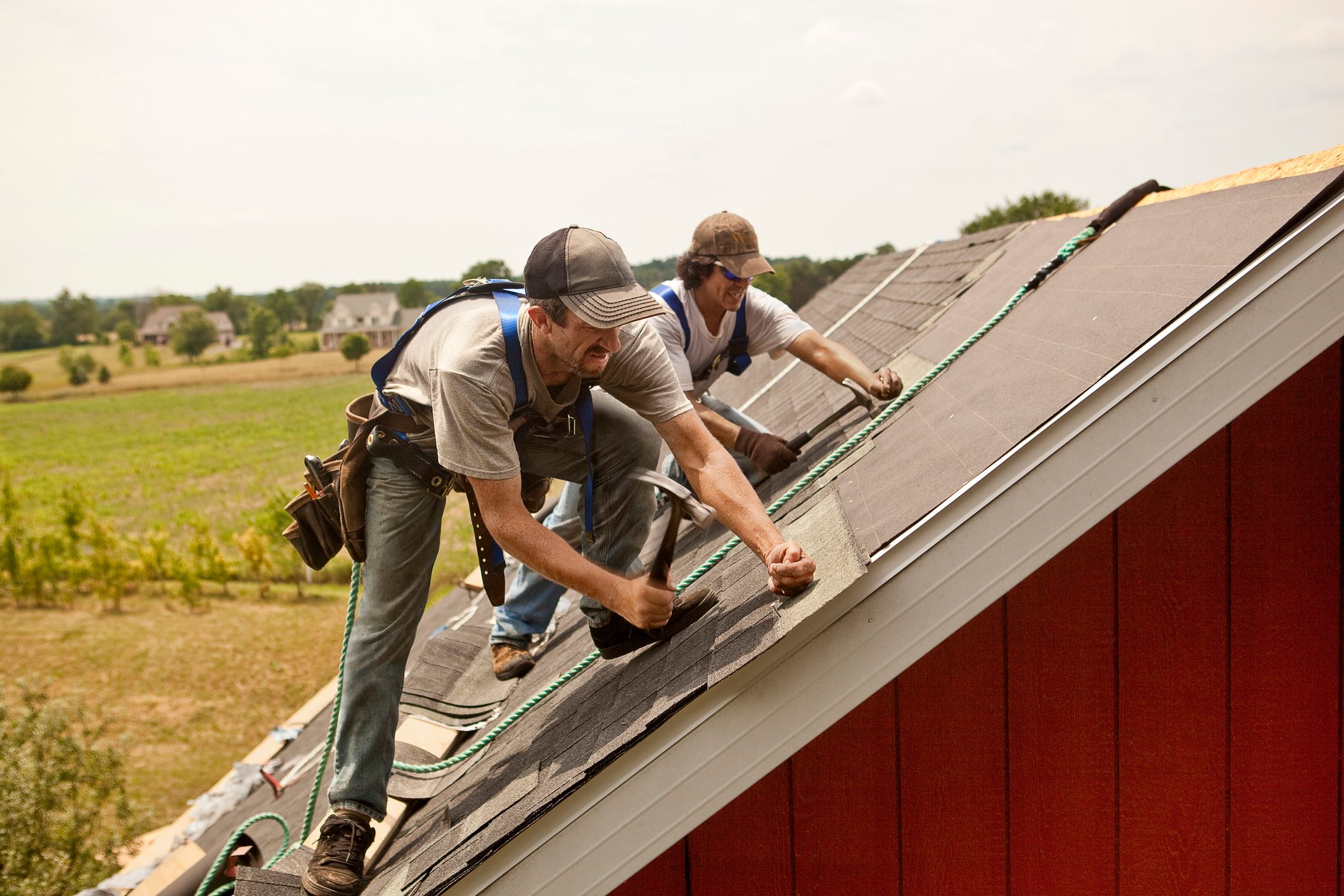 Two men working on repairing a home's roof.