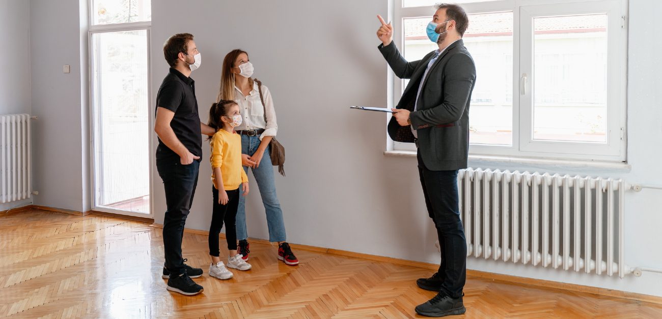 A real estate agent shows a home to a man, a woman, and their child.