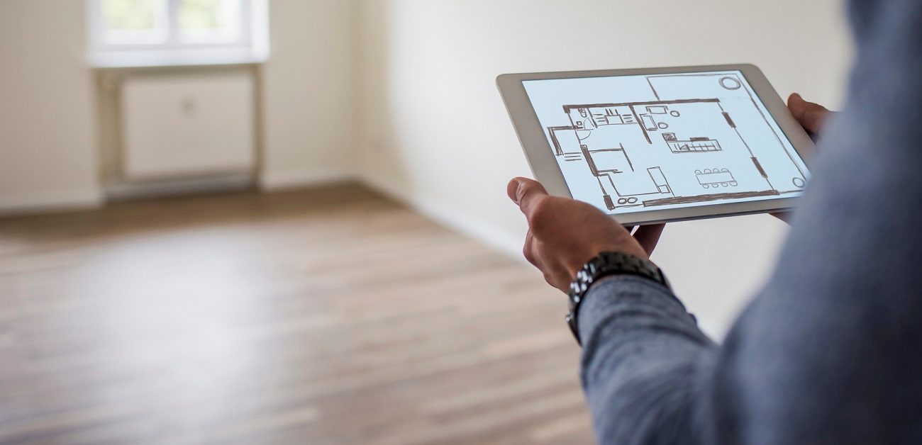 Man in new home holding tablet with floor plan