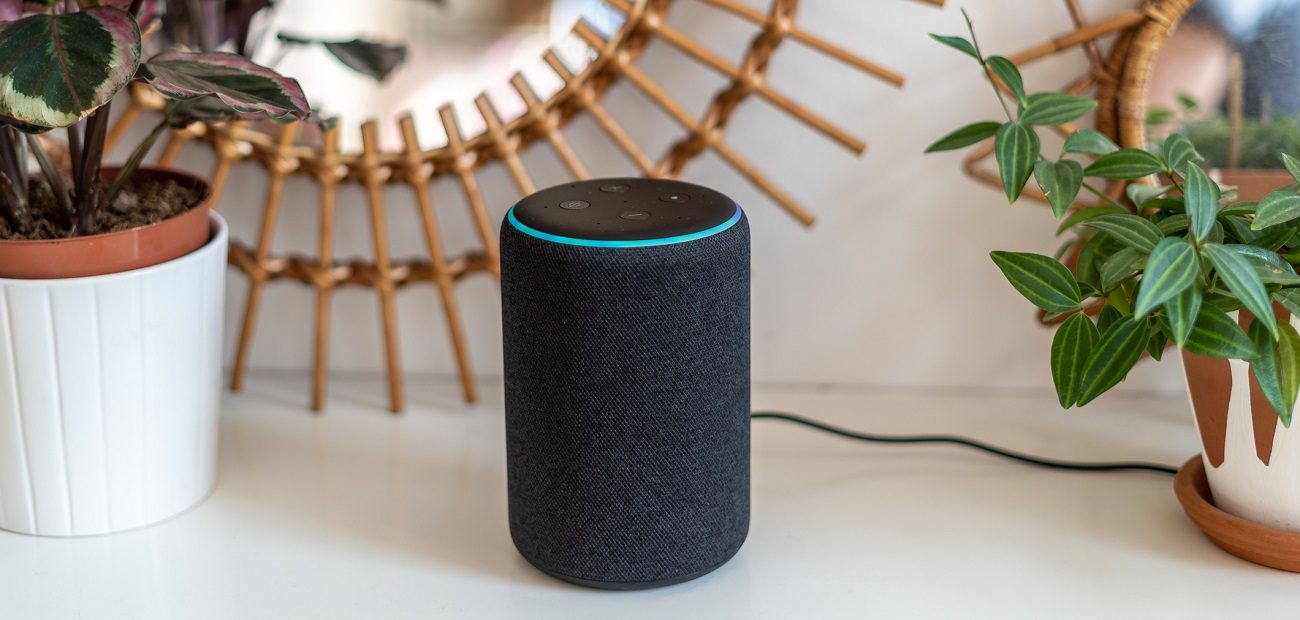 Amazon Alexa Echo Plus on a white table with green plants in the background
