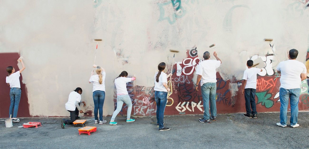 Volunteers painting over graffiti wall