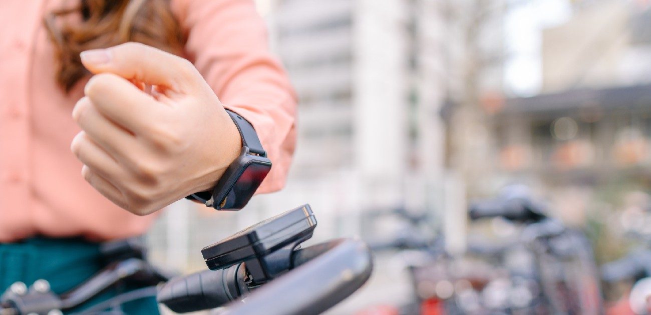A picture of a woman on her bike showing her smart watch.