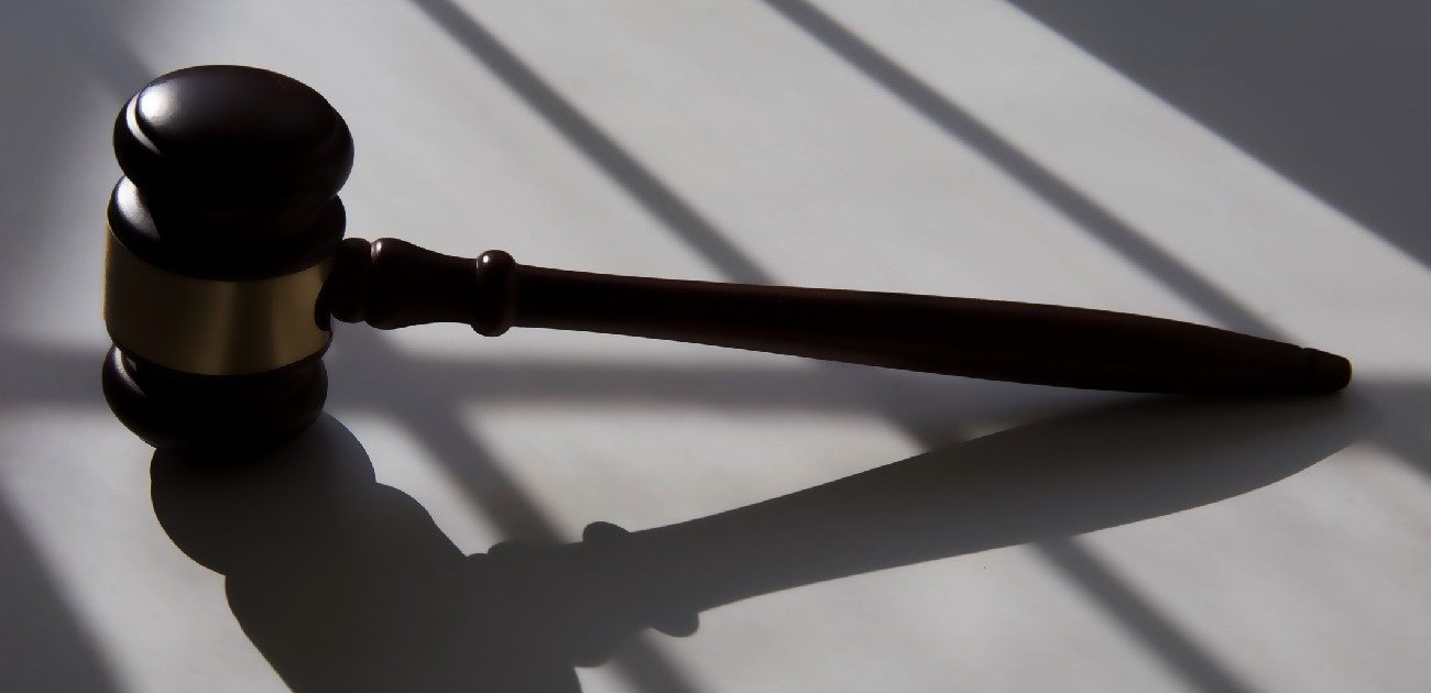 A picture of a gavel lying on a desk with angled lighting coming from behind it casting long shadows.