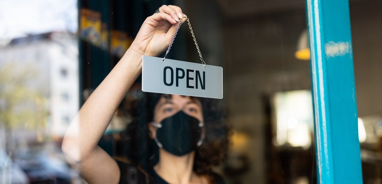 Business owner with face mask hanging an open sign