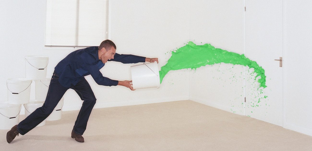 Man throwing bucket of green paint at door