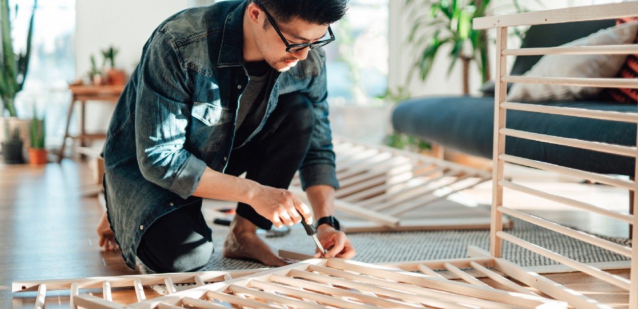 A man assembles wooden frames for a piece of furniture