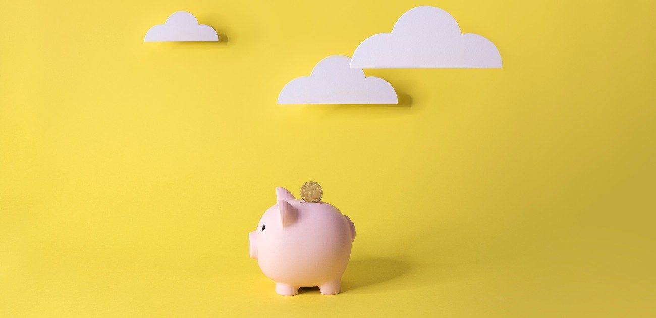 A picture of a piggy bank flying in a yellow-colored sky with three clouds.