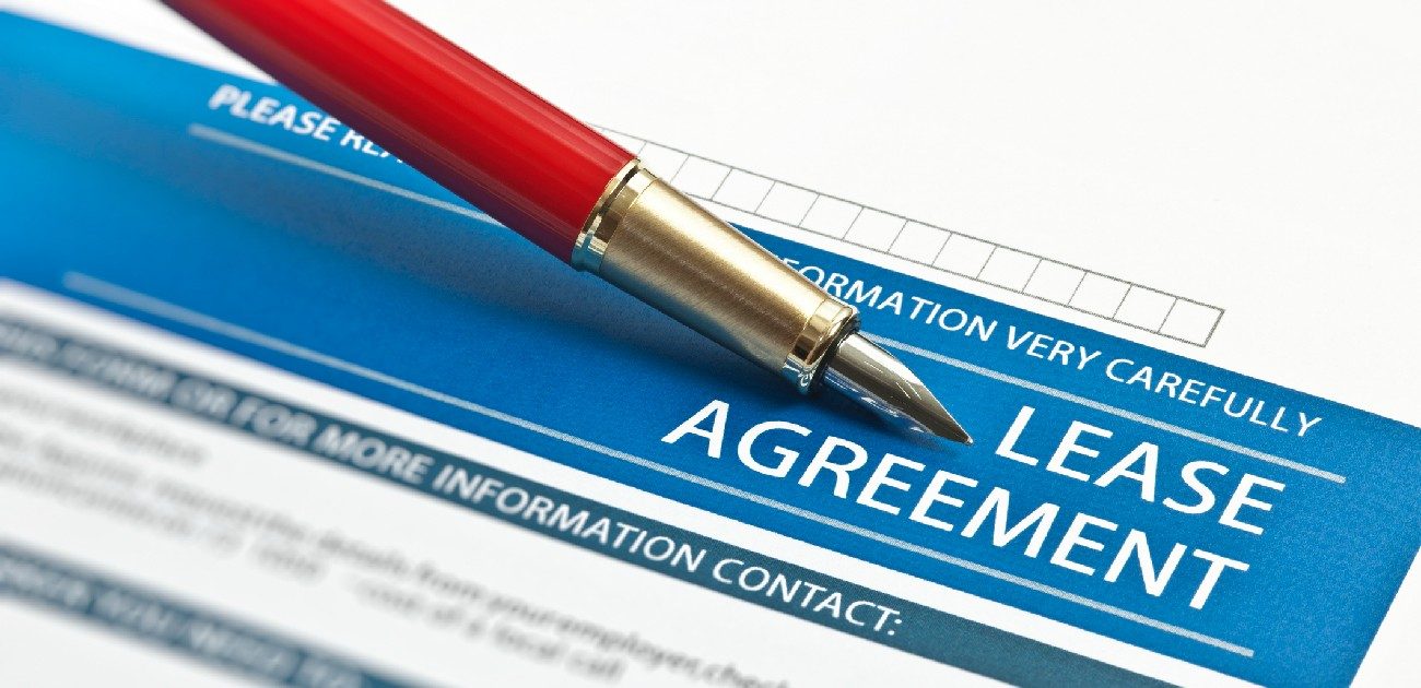 A picture of a lease agreement with a pen being pointed toward the top of the document.