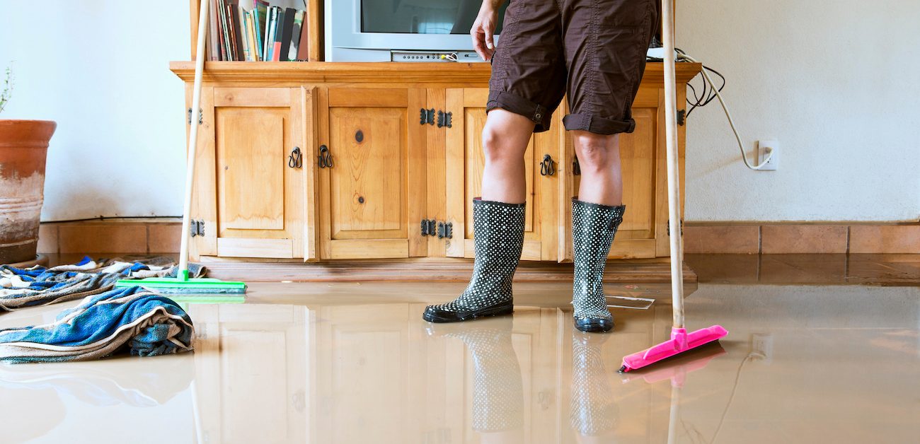 Woman wearing rainboots stands in flooding house 
