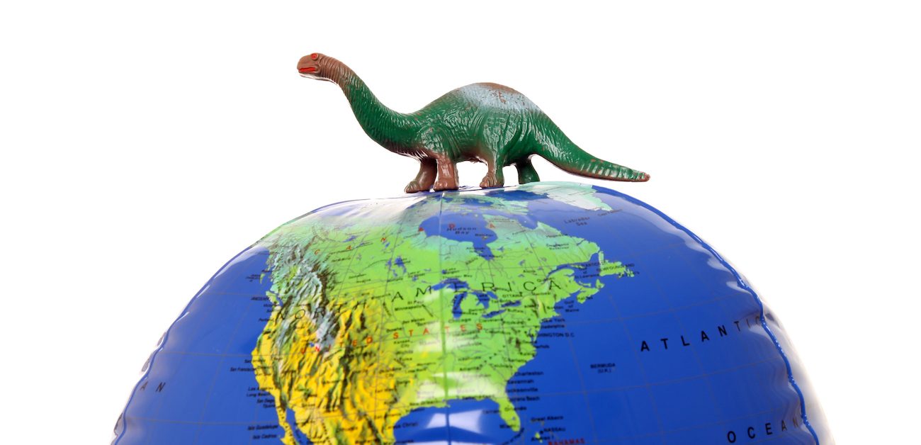 Toy dinosaur on top of inflatable globe