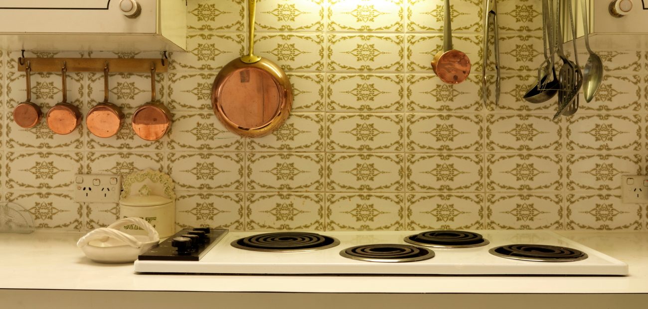 An electric stove with cookware hanging on the wall