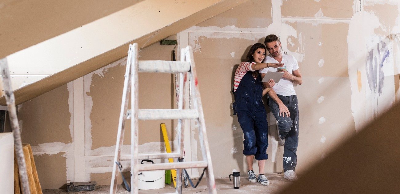 A man and woman remodel a room in their house.