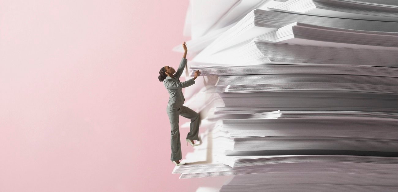 Businesswoman climbing stack of documents