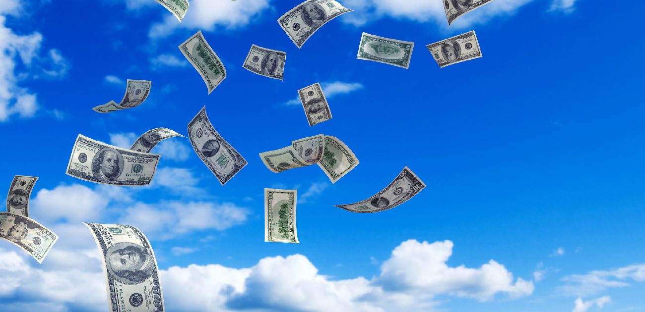A picture of money falling from above, with a blue sky and clouds in the background.