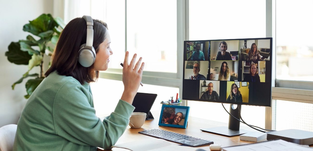 A woman sits at her computer while on a video call with multiple coworkers.