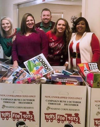 Fayard and associates pose by toys collected for charity