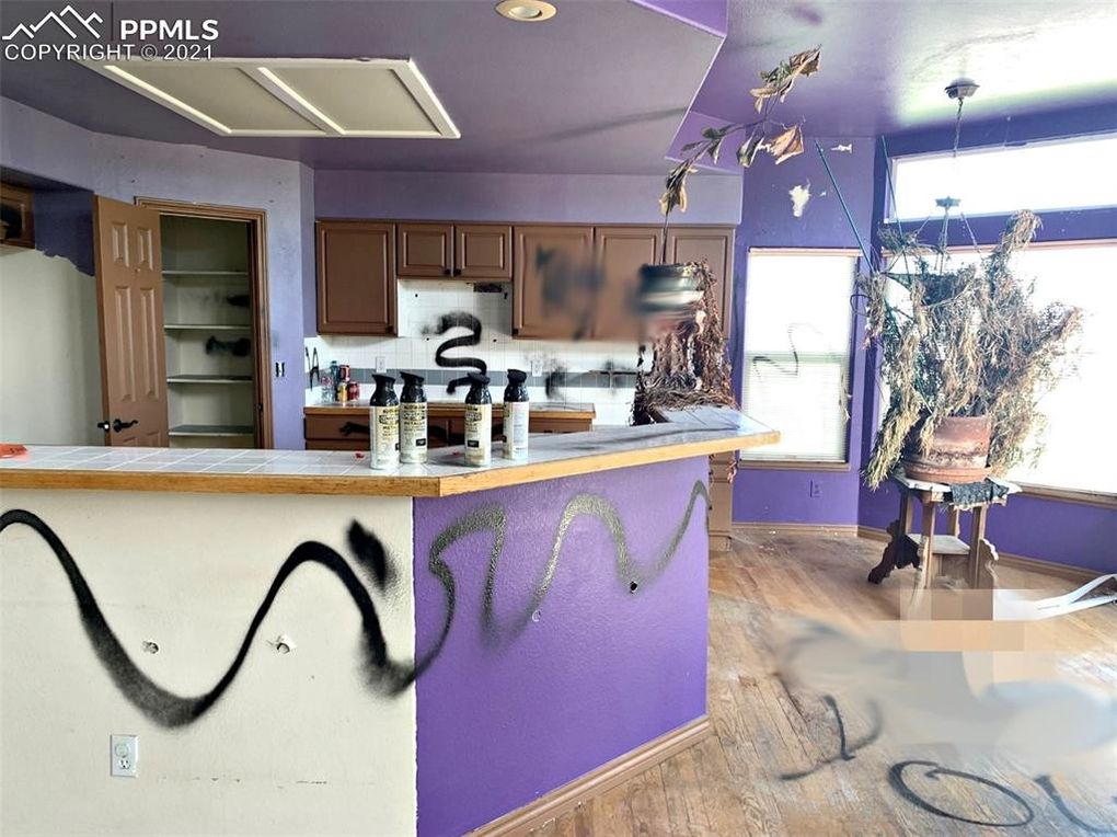 An photo of the interior of the home with black spray paint graffitied on the floors and walls